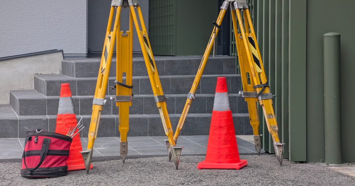 Surveying tripods and traffic cones set up for a land survey
